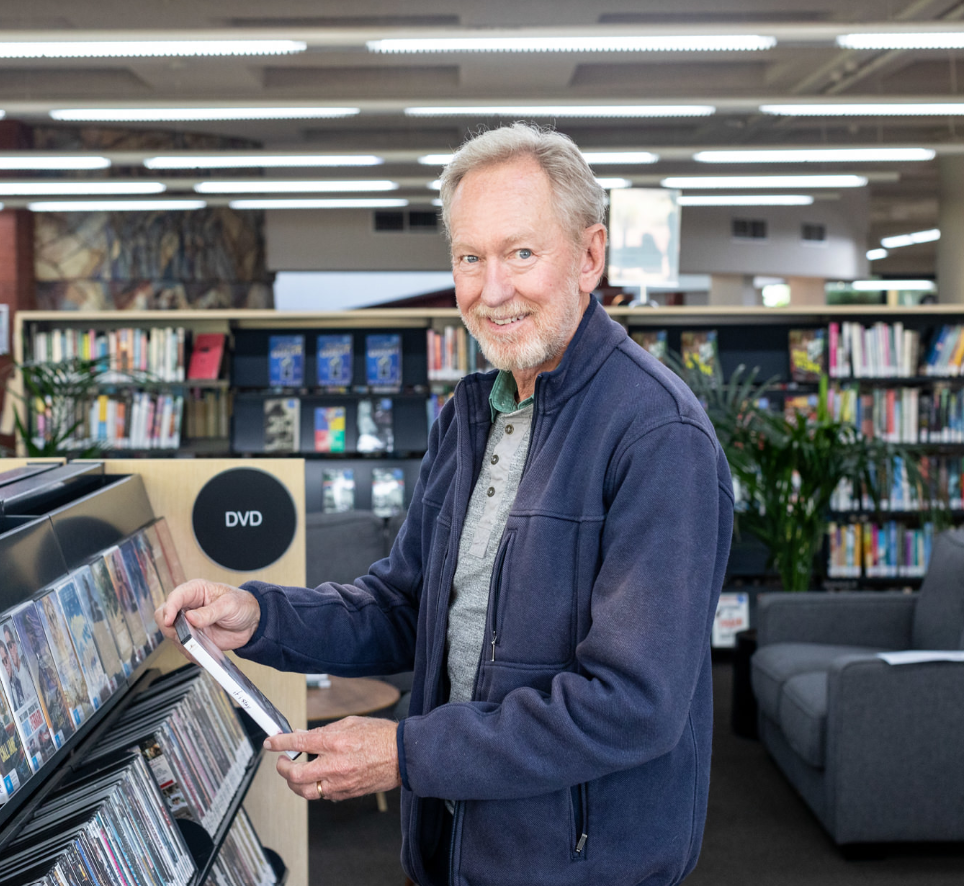 A man holding a book in Brighton library and smiling 