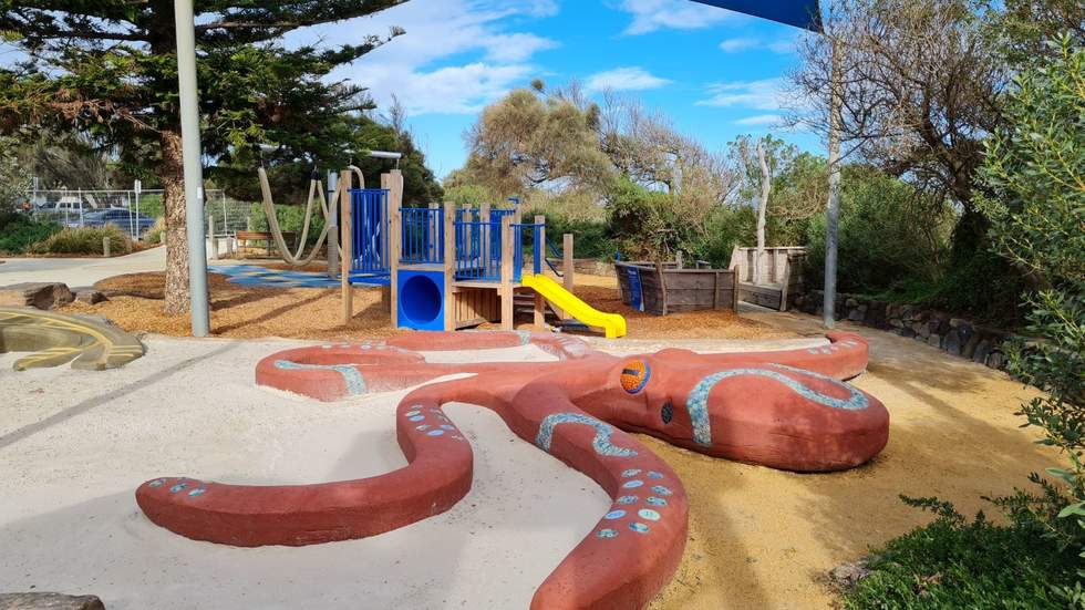 Beach Park playground showing a large concrete octopus, slide,shade sail and sand