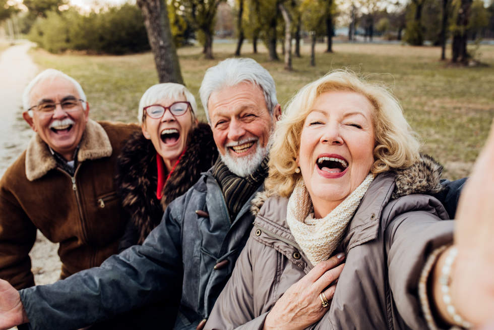Senior couples laughing on a bench in a park