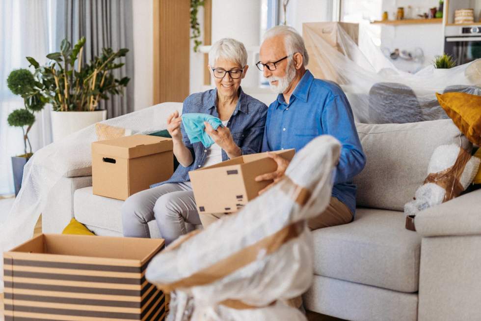 Older couple sitting on a couch going through a box wider image 
