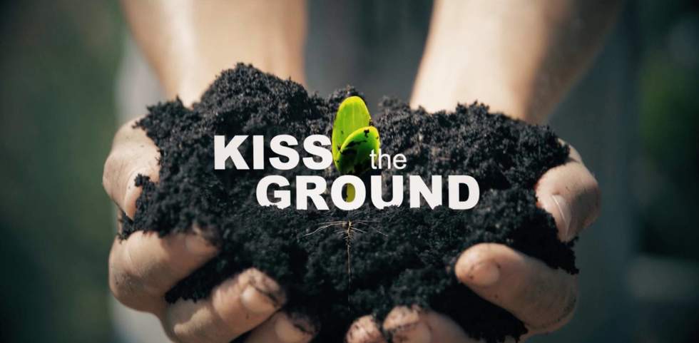 Two hands holding soil Kiss the ground promotion title 