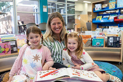 A mother with her two children at Beaumaris library sitting down reading a book