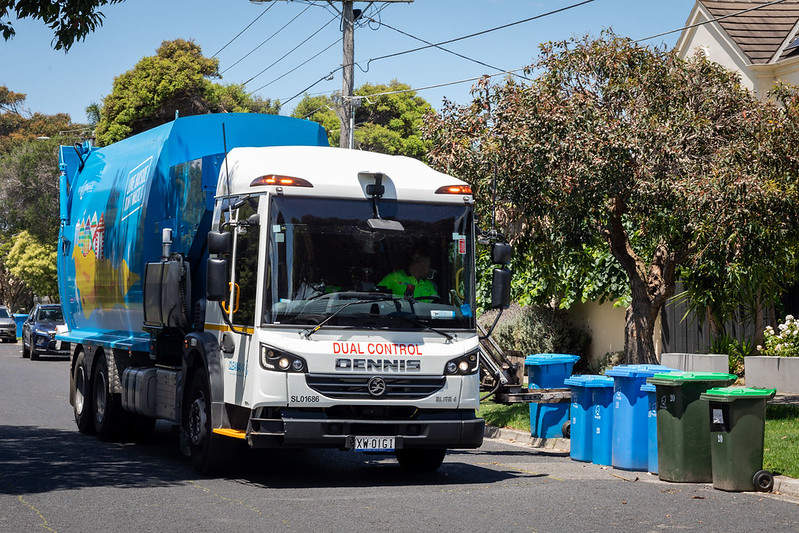 Blue and white recycling truck collecting bins 