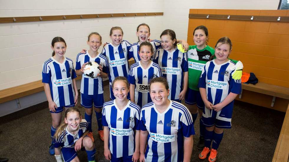 Soccer girls in blue and white in the changeroom in a group photo.