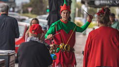 Performing artist dressed as an elf entertaining residents on the street.