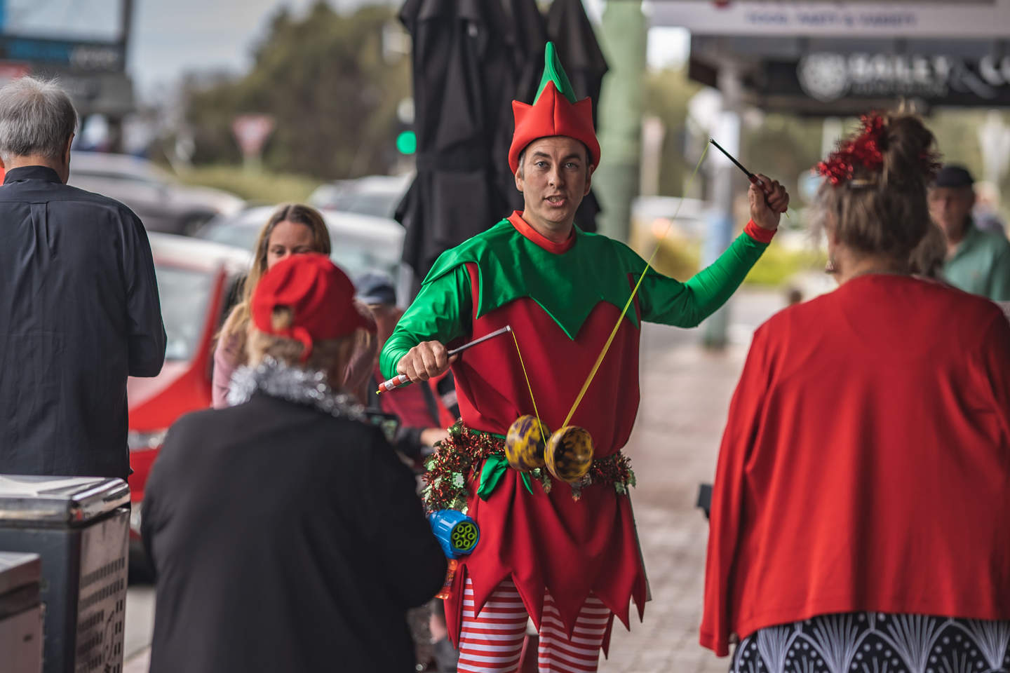 Performing artist dressed as an elf entertaining residents on the street.