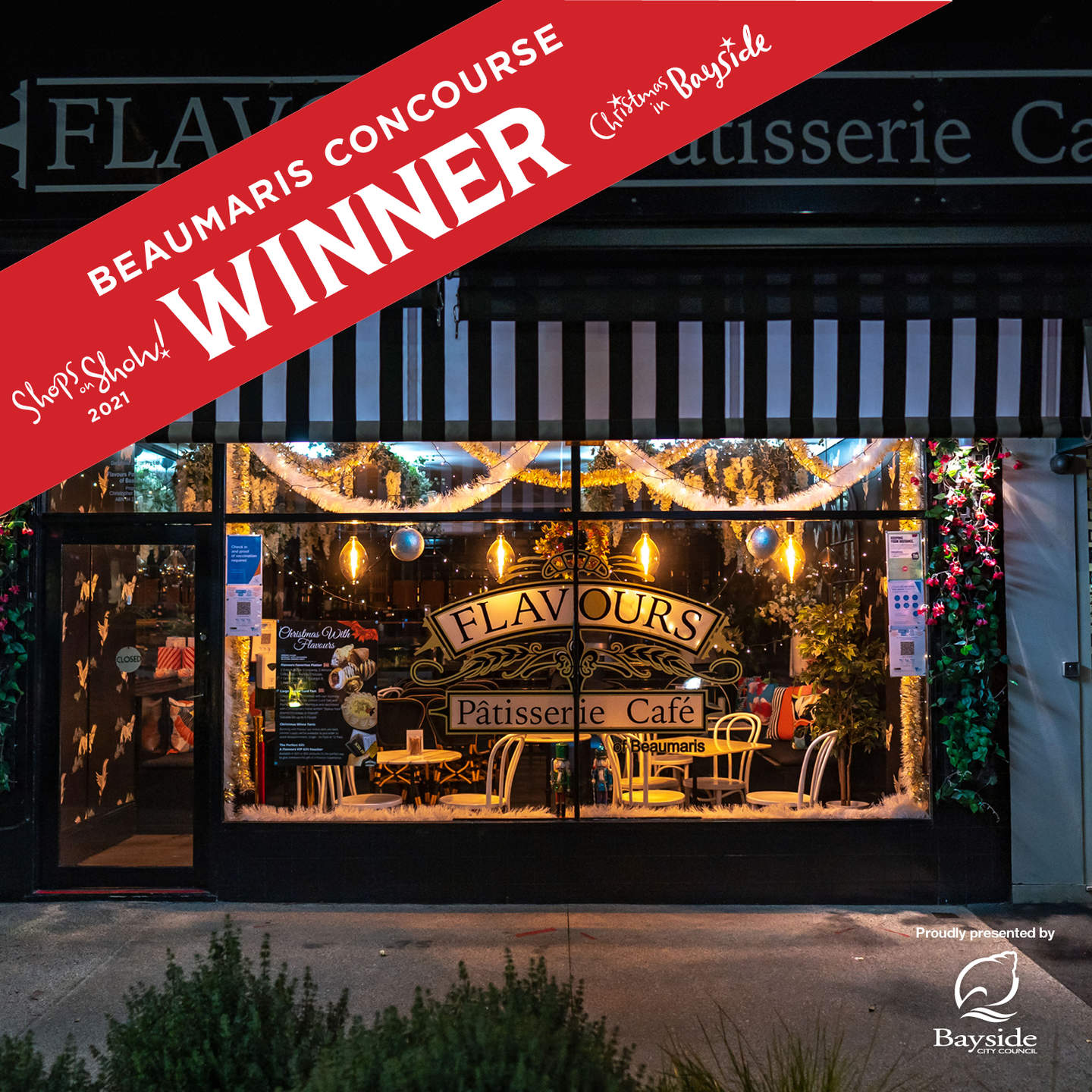 Shops on Show Beaumaris Concourse winner. Window shopfront of Flavours Patisserie Cafe decorated with tinsel, baubles and handing yellow lights.