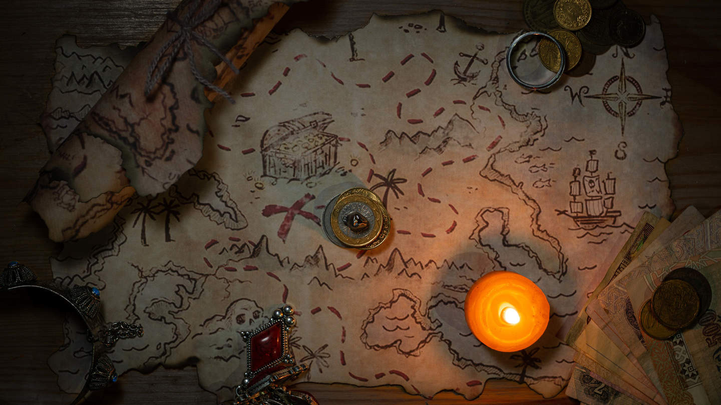 Treasure map laid out on a table with a candle 
