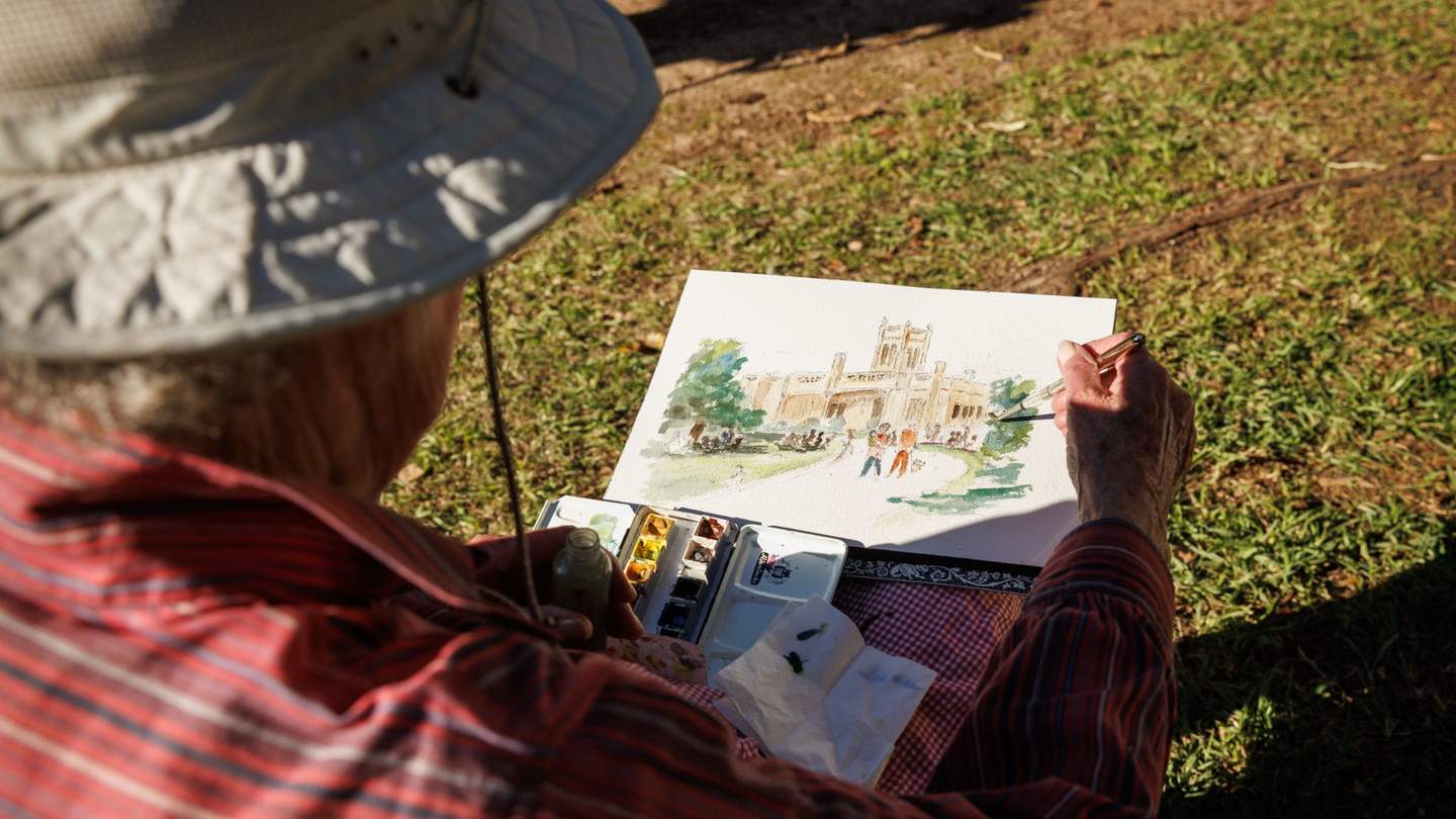 A man painting a picture of Billilla mansion and the gardens