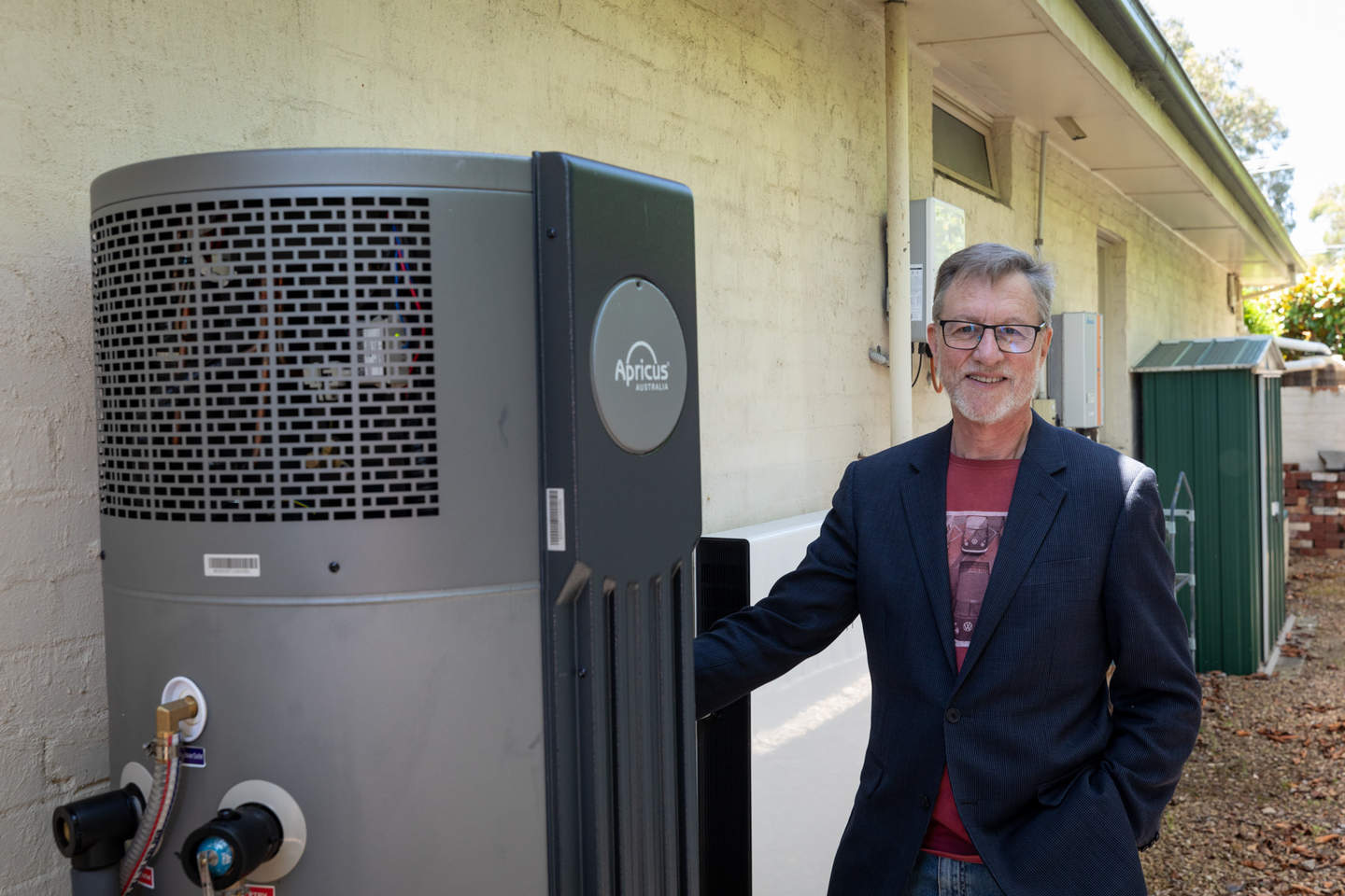 Bayside resident Kris stands next to his hot water heat pump