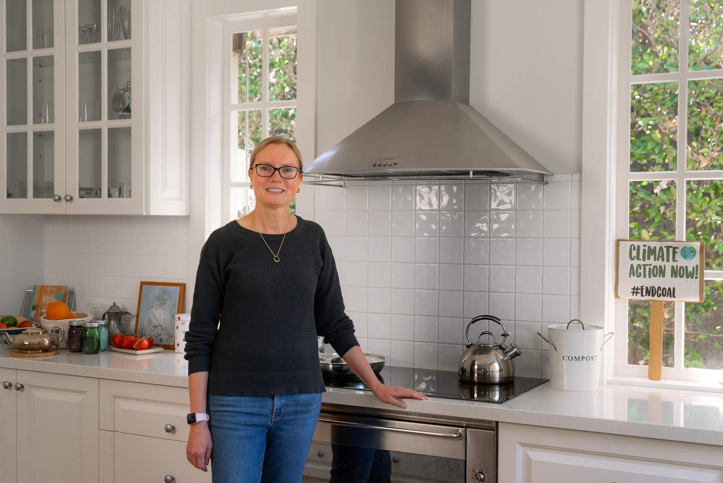Kylie, a caucasian woman, stands in front of her induction cooktop in her bright white kitchen