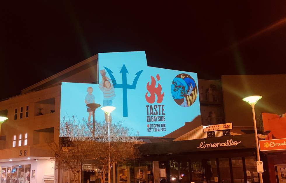 Image of children playing projected onto a wall with Taste of Bayside logo