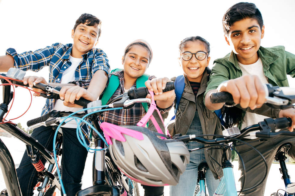 Four young teens on bikes smiling at the camera