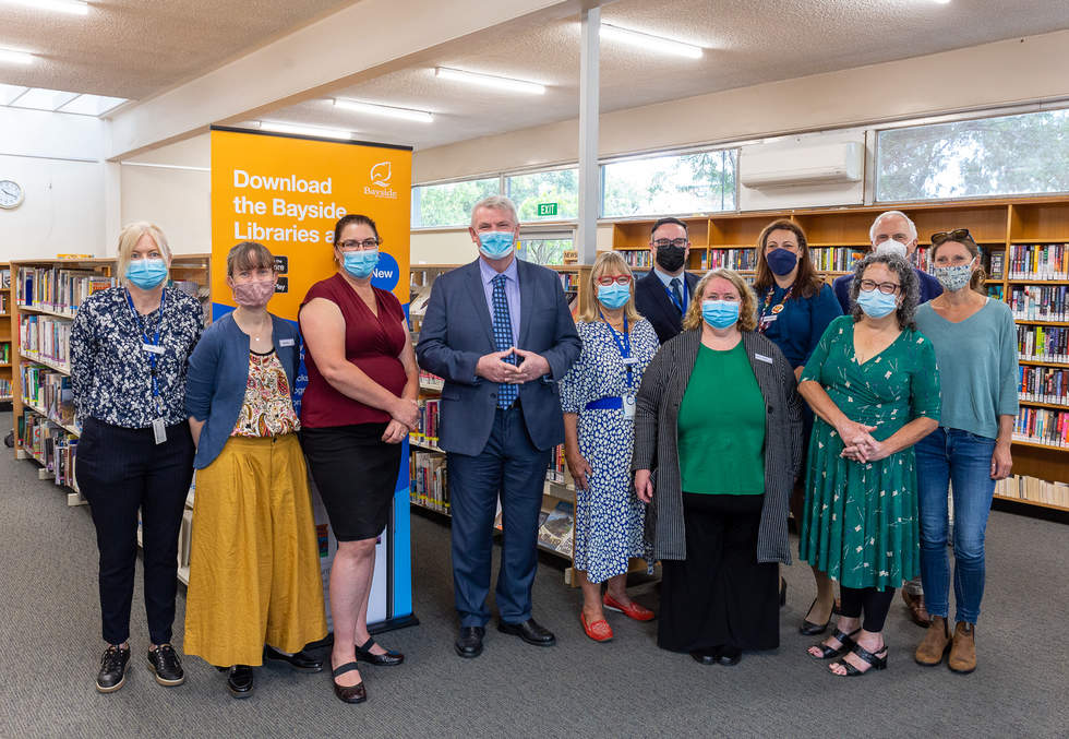 Government Minister and library staff standing in library, all masked