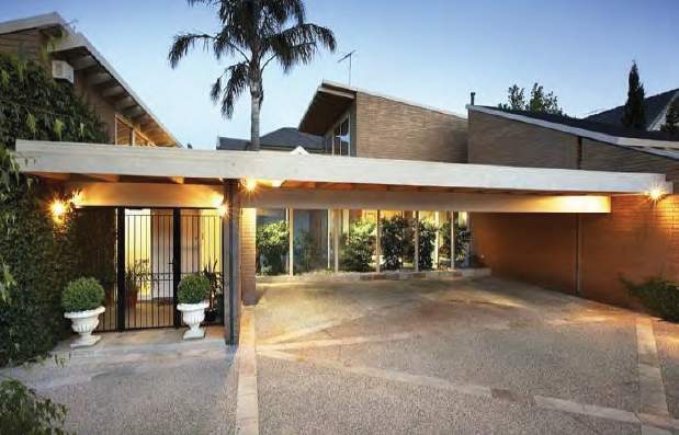 black iron gates and plants front a mid century modern property