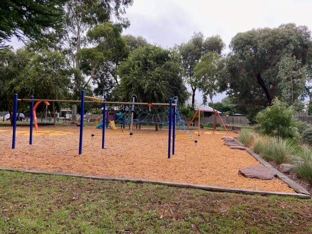 Playground swings tan bark trees grass