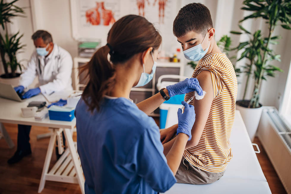 Female nurse giving immunisation to young teenager- stock photo