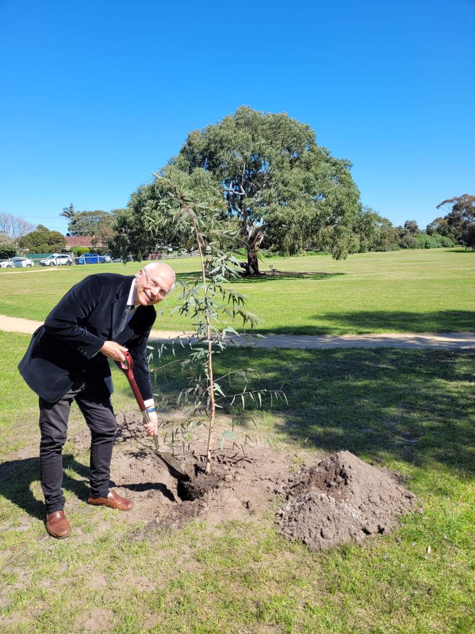 Mayor Cr Alex Del Porto smiling whilst planting a tree