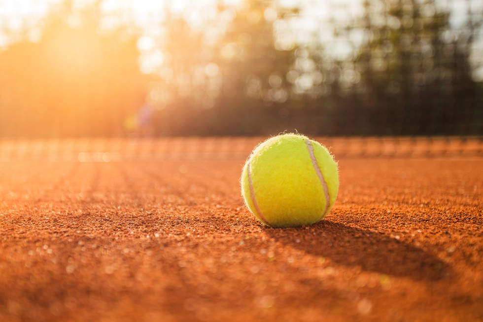 Yellow tennis ball on a red clay court