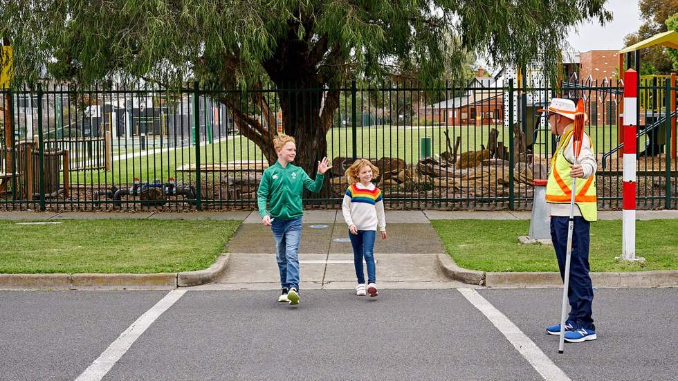 Two Children crossing the road with crossing supervisor 