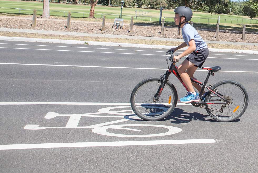Young boy cycling down the road in a bike lane