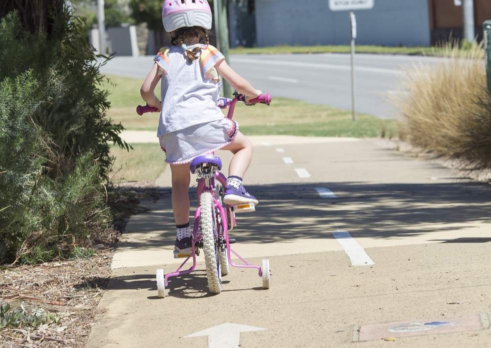Young girl on a bike with training wheels on Bay Trail bike path alongside Beach Road