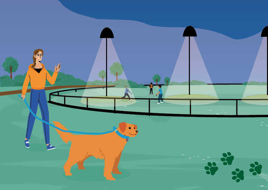 Animated image of a person walking their dog at a sports ground at night time with the lights on. Kids in background playing on the oval.