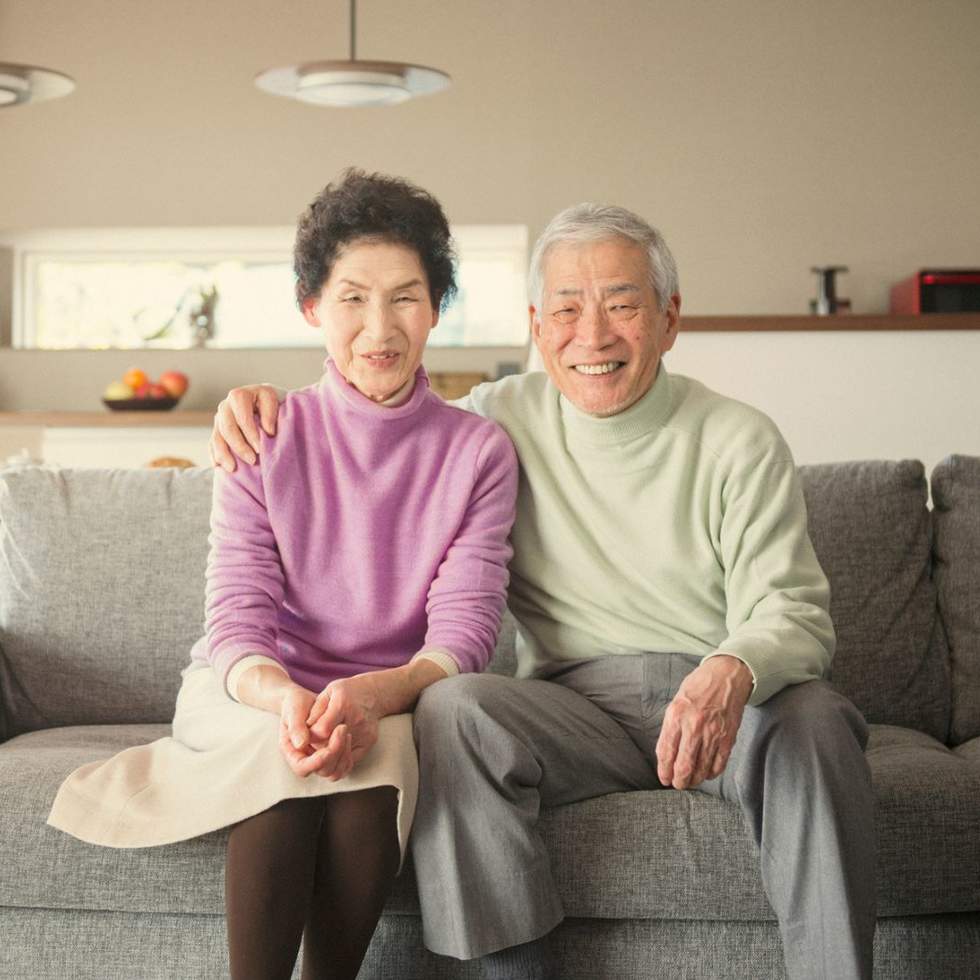 Senior couple sitting arm in arm on the sofa.