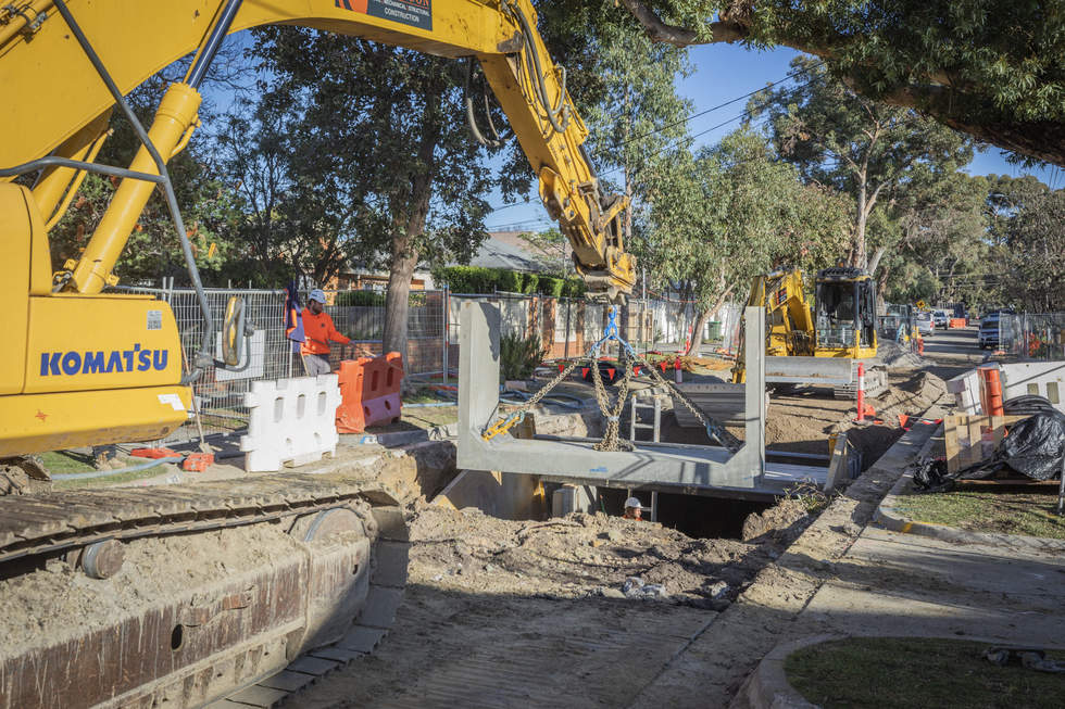 Crane lifting large culvert into the ground