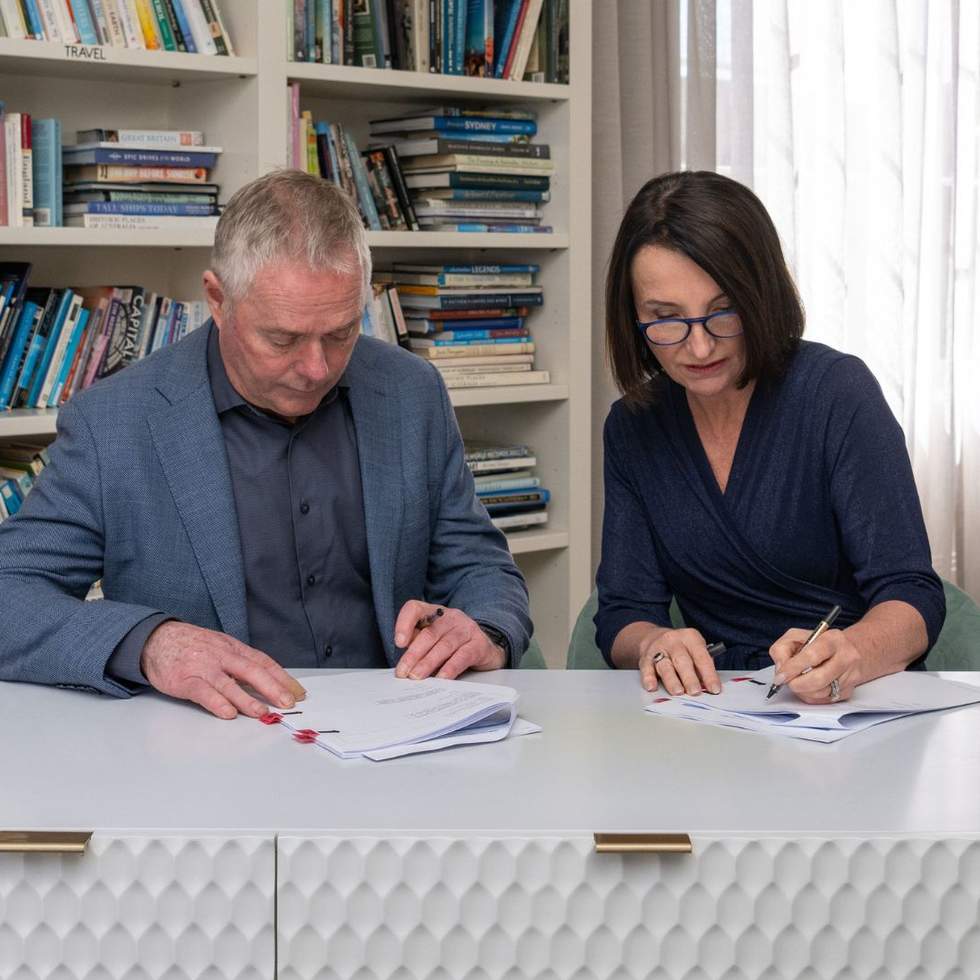 A man and a woman signing an agreement in a library.